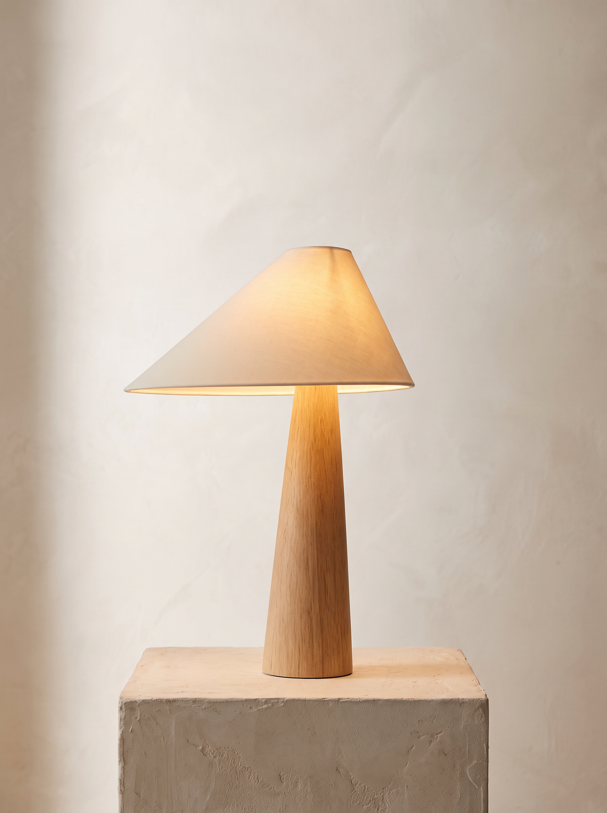 Mushi table lamp lit warm on plaster plinth